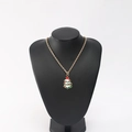 Golden Christmas tree pendant necklace with green enamel on a black mannequin display - Christmas Tree Type A