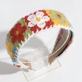Close-up of hand-knitted floral headband with colorful embroidery on an acrylic stand - Red Green Yellow Blue