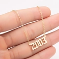 Close-up of golden gothic year 2003 pendant on a delicate stainless steel chain - 2003 / Gold