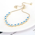 Detail eines Evil Eye Armbands mit blauen Emailleperlen und goldener Verstellkette - Weiß
