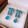 Dettaglio di orecchini a fiocco blu con cristalli in una scatola per gioielli elegante - Stile Pendente a Fiocco con Ago in Argento / Blu Argento