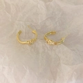 Detailed macro view of golden knot earrings on a textured white background paper - Minimalist Knot Style
