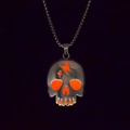Detailaufnahme eines Totenkopf-Anhängers mit orangem Blitz auf einer schwarzen Kette - Orange