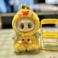 Labubu doll wearing yellow duck plush jumpsuit outfit and sitting by a mini chair - Cloud-like Fluffy Yellow Duck / First And Second Generation Keychains Are Compatible With La Cloth Dolls. Dolls Not Included.