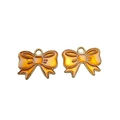 Close-up of orange enamel bow pendants with gold metal borders for DIY jewelry making - Orange