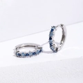 Orecchini a cerchio in argento con zirconi blu quadrati su uno sfondo bianco - Zirconia Blu / Argento