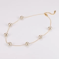 Dettaglio della collana dorata con otto perle lucenti su un elegante sfondo bianco - Collana Oro