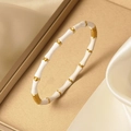 Détail du bracelet en bambou doré 18K avec émail blanc sur un support de soie élégant - Blanc