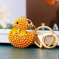 Close-up of yellow pearl duck keychain with golden bow and sparkling rhinestones - Yellow Pearl Duck