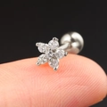 Detailed close-up of a silver flower stud earring with clear zircon gems on a fingertip - CC003-11 Silver Flower