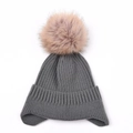 Detailed knit texture of dark grey winter beanie with fluffy pink faux fur pompom - Gray