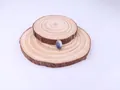 Blue natural stone pendant with gold wire wrapping displayed on a wooden slice - 8x26mm / Blue Sodalite