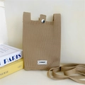 Detail of khaki knitted phone bag featuring a metal buckle and STANNUM label on textured fabric - Camel
