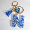 Macro shot of resin letter N keychain with blue stones, gold foil and blue tassel - Letter N