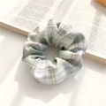 Green and white checkered fabric scrunchie on an open book with soft natural light - JK Cedar
