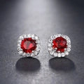 Macro detail of silver stud earrings featuring round red zircon and halo diamond setting - Red
