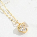 Macro shot of gold heart pendant with zircon on white leather background - White