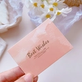 Pink gradient greeting card with gold foil lettering held against a soft floral background - Ink Orange