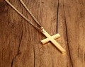 Polished gold stainless steel cross pendant necklace on a dark wood grain background - Gold Pendant + Chain