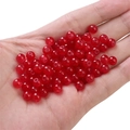 Vibrant red round glass beads for DIY jewelry making held in palm against white background - Red approx 50pcs/pack
