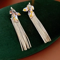 Detalle de pendientes con borla plateada y diseño de hoja esmaltada morada y amarilla - Plateado
