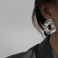 Detailopname van zilveren holle ovale oorbellen met geplooide textuur en metaalglans - Zilver (Zilveren pin)