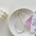 Beaded phone charm with white faux pearls and transparent butterfly pendant on a tray - Pearl Crystal Butterfly Bracelet