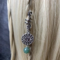 Detailed close-up of a silver spiral hair ring with sun charm and green bead on blonde hair - Sun Green Bead