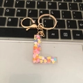 Macro shot of resin letter L keychain with colorful heart glitter on a keyboard - L
