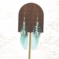Detail of bohemian long feather earrings with turquoise beads on a wooden stand - Mint Green