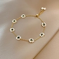 Pulsera dorada con flores de perlas blancas y gemas verdes sobre fondo de seda - Nueva Pulsera De Oro Mfs145