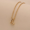 Macro view of gold L-letter pendant necklace with sparkling inlaid cubic zirconia - Letter L