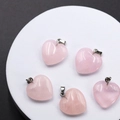 Five heart-shaped rose quartz pendants with metal loops on a white round display - Rose Quartz