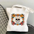 Close-up of skull and floral print on off-white canvas tote bag placed on a black chair - Floral Skull Sketch