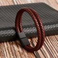 Detail of a brown braided leather bracelet with a black magnetic clasp on a dark wallet - Coffee