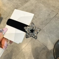 Dettaglio di un fermaglio per capelli in velluto nero con strass a stella scintillanti - Pentagramma