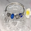 Close-up of silver-tone bracelet with blue glass beads and dreamcatcher heart charms - Blue