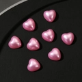 Detailed view of eight pink pearlescent 3D heart beads on a black textured surface - Large / Pink