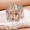 Dettaglio di un bracciale a maglie argentate con stella in smalto viola e trama metallica - Viola