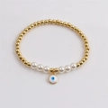 Détail d'un bracelet de perles dorées avec perles blanches et pendentif œil maléfique - Blanc
