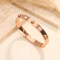 Roségoldfarbenes Titanstahl-Armband mit weißem Perlmutt-Kleeblatt und Nieten-Details - Roségold