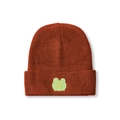Detailed knit texture of rust red beanie with cute green frog patch holding a star - M (56-58cm) / Caramel color