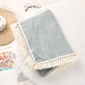 Detail of grey-blue crinkle cotton baby blanket with thick beige tassel trim on plush rug - Bean Green / 80*65 cm