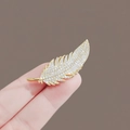 Broche en forme de plume dorée sertie de cristaux brillants vue de près à la main - Style Plume Dorée (0197)