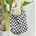 Stylish black and white checkered canvas tote bag for women shown in a casual lifestyle setting - Black