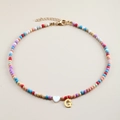 Detail of colorful beaded necklace with white heart bead and gold letter G pendant - Letter G