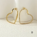 Nahaufnahme der goldenen Herzohrringe mit funkelnden Zirkonia-Steinen und glänzendem Finish - Gold/Weißer Zirkonia