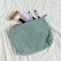 Light blue corduroy makeup bag with zipper closure shown with cosmetics inside - Light Green