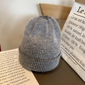 Thick grey marl knit beanie hat with warm wool texture on a wooden table display - Elastic / Mixed Black