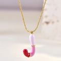 Detailed macro view of a gold J-letter enamel pendant with pink and white gradient - Letter J